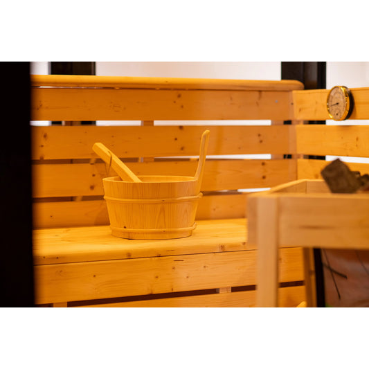 Wooden bucket and ladle on a wooden bench in a sauna setting