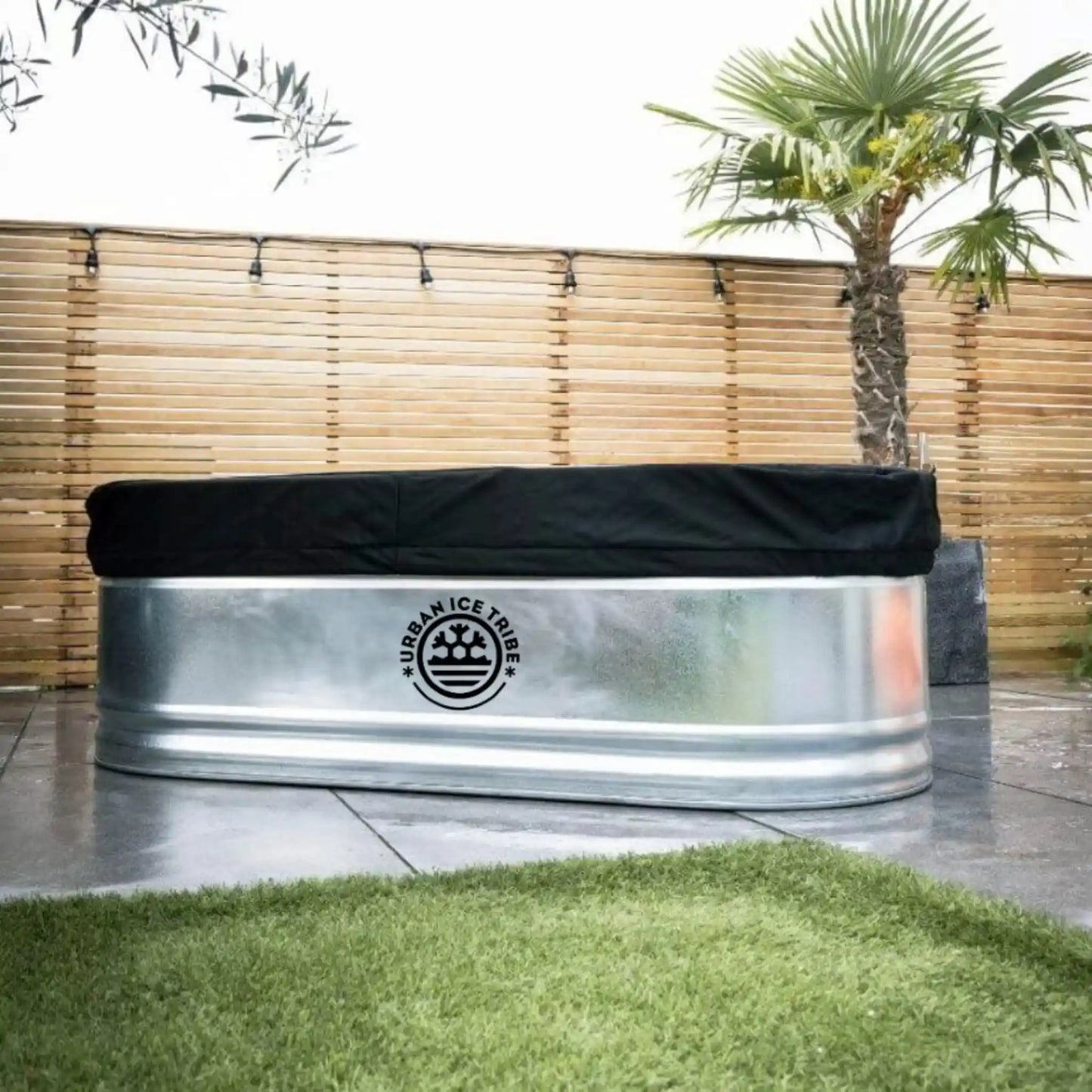 Steel ice bath and black cover, with Urban Ice Tribe branding, in a garden setting.