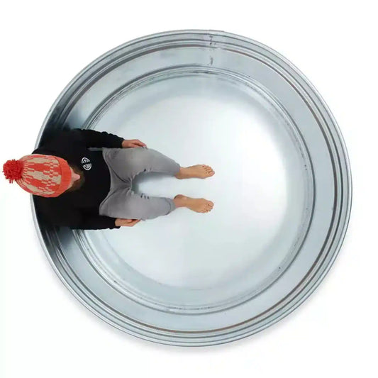 Person wearing a red beanie and black jacket inside a metal ice bath on a white background