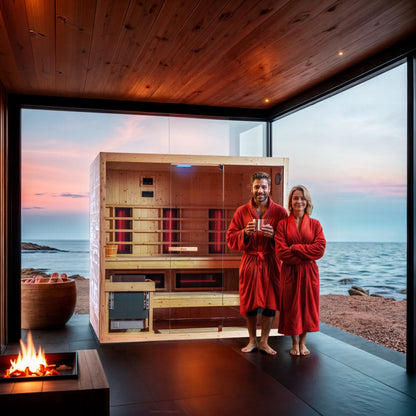 Two people in red robes standing in a sauna with a scenic view of water and sky.