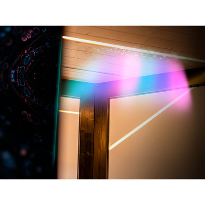 Colourful light projection on a wooden sauna wall with electronic equipment on the left.