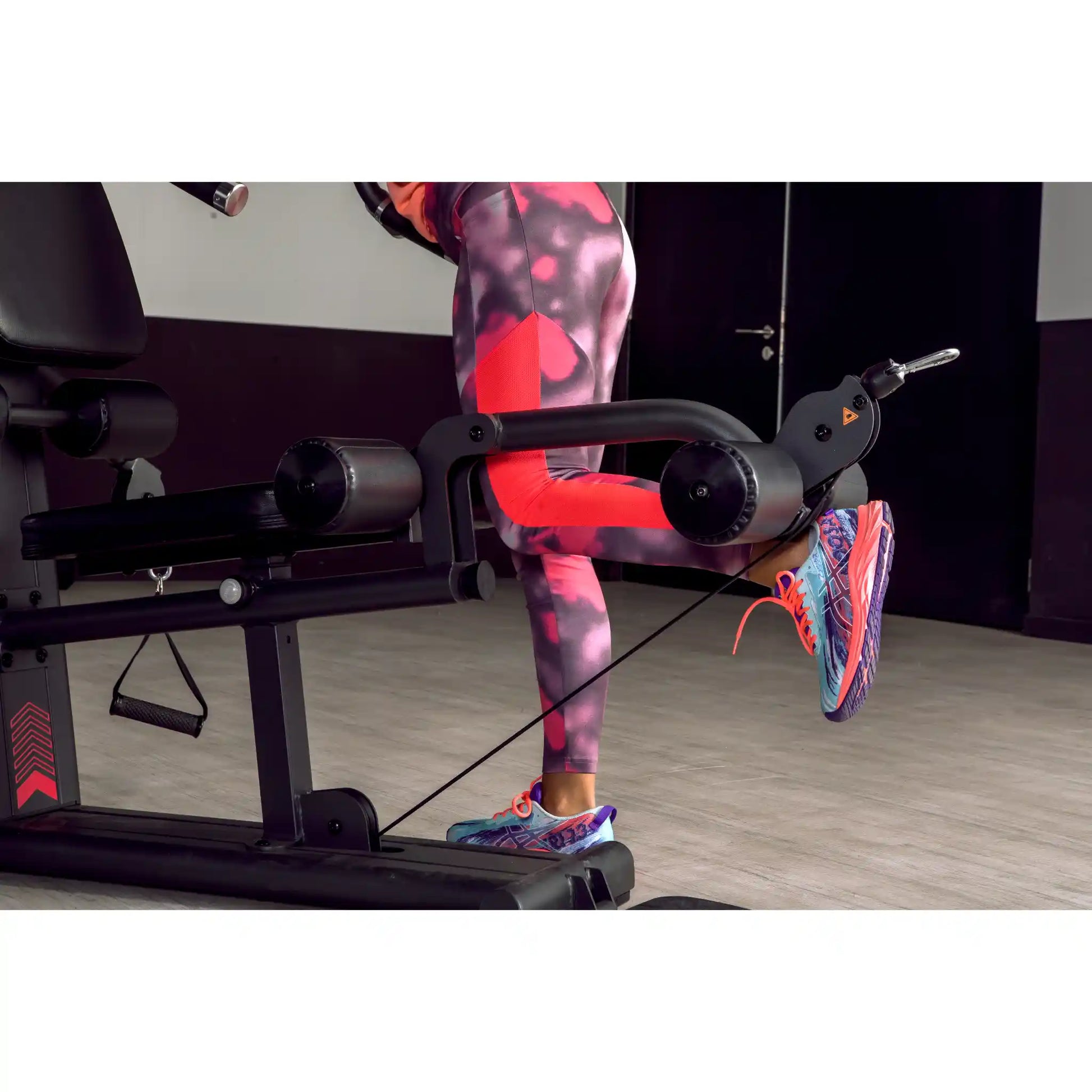 Person using leg curl function on multi gym