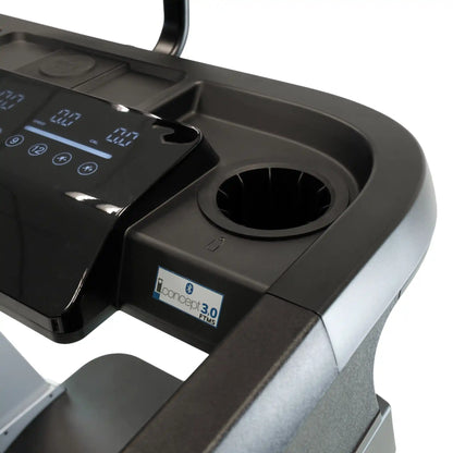 Close-up of a treadmill with a digital display and cup holder on a white background