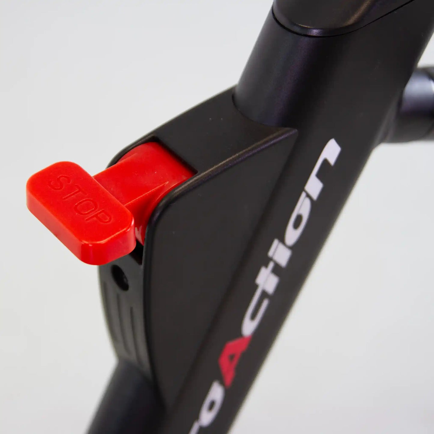 Close-up of a black exercise bike with a red 'Stop' button on a light gray background