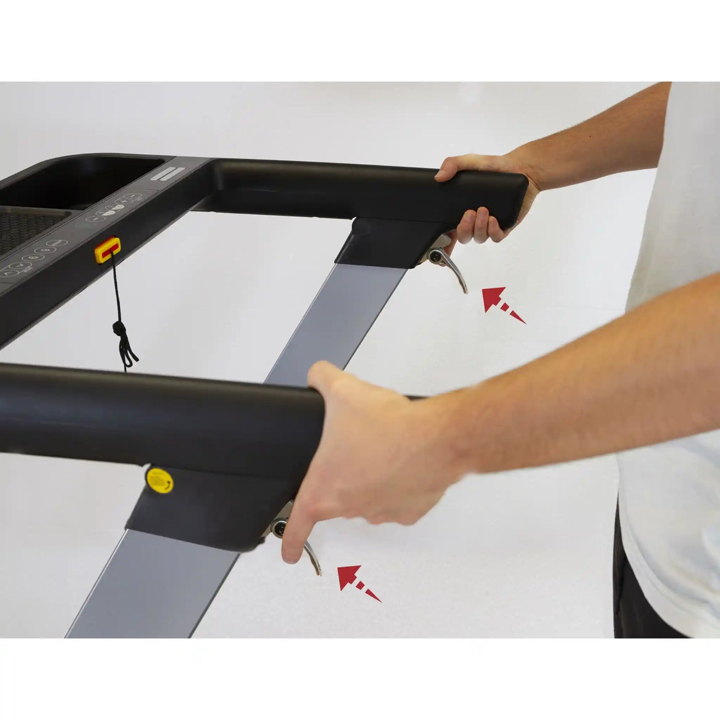 Person adjusting a treadmill with close-up of hands and treadmill parts.