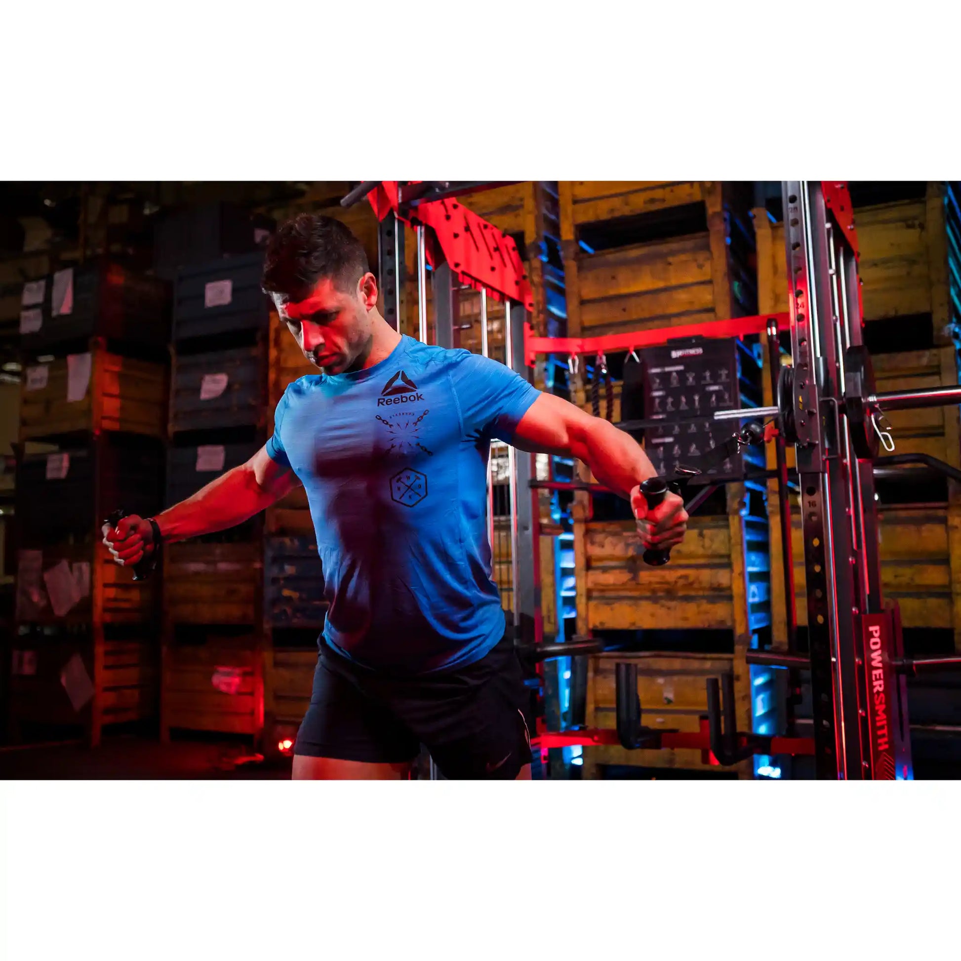 Man exercising with handles from pulleys on a multi gym in a warehouse setting
