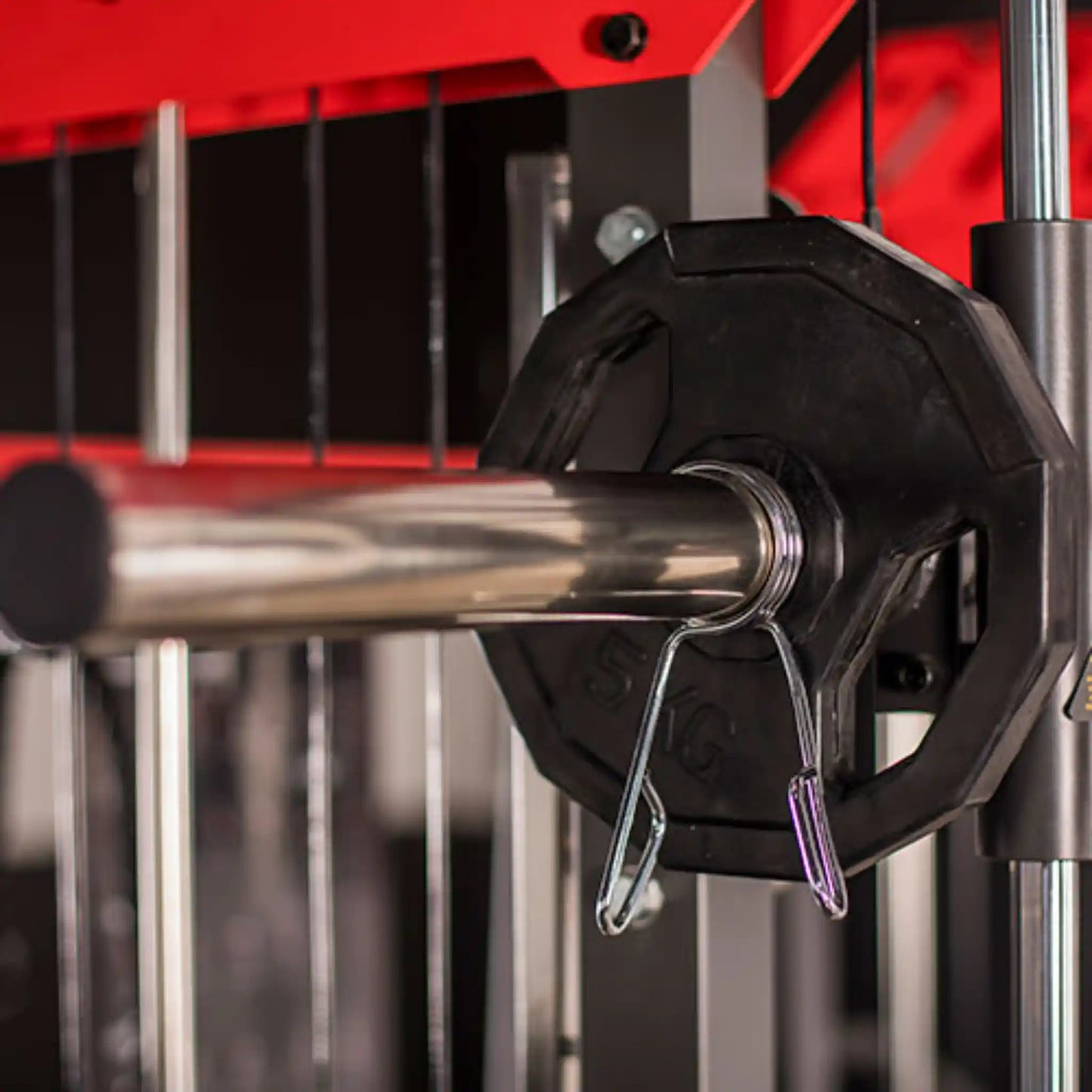 Close-up of a barbell with weight plates on a red weight rack.