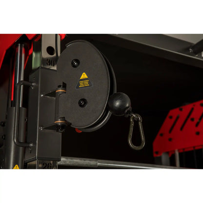 Close-up of a mechanical pulley system  on a multi gym with a warning label on a dark background.