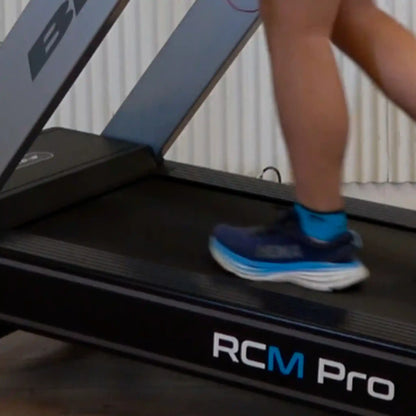 Person using a treadmill labeled 'RCM Pro' with a neutral background