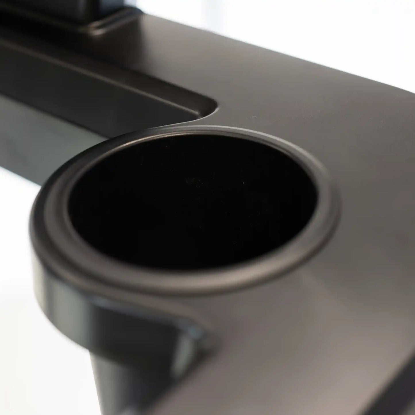 Close-up of a black cup holder on treadmill with a white background
