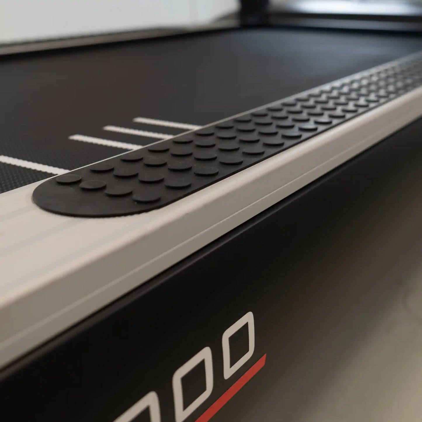 Close-up of a treadmill with a focus on the running belt and brand logo.