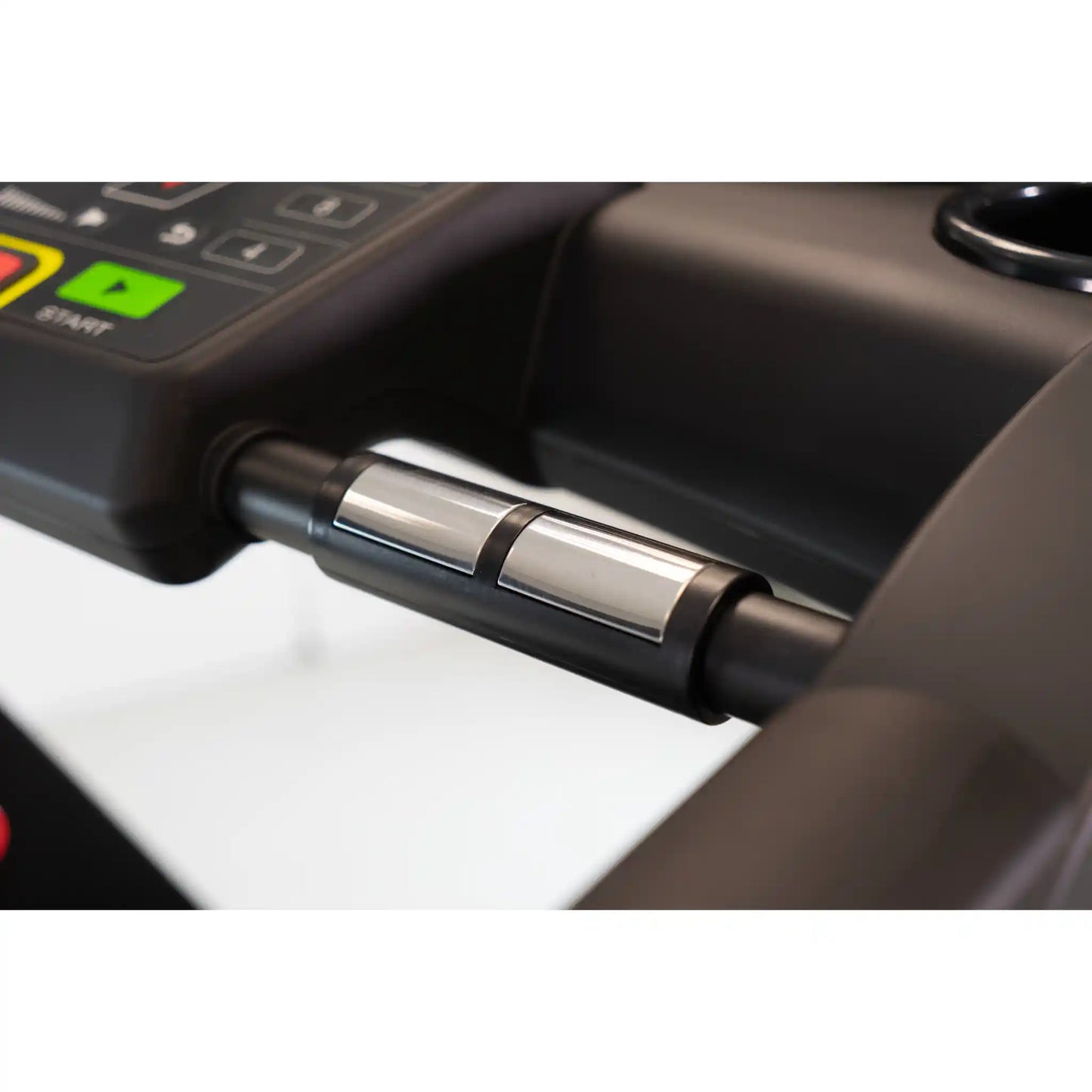 Close-up of a treadmill handle with sensors and a control panel in the background