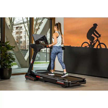 Woman using a treadmill with a silhouette of a cyclist on a wall in the background.