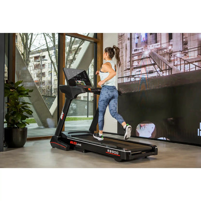 Woman using a treadmill with a large screen displaying an urban scene.