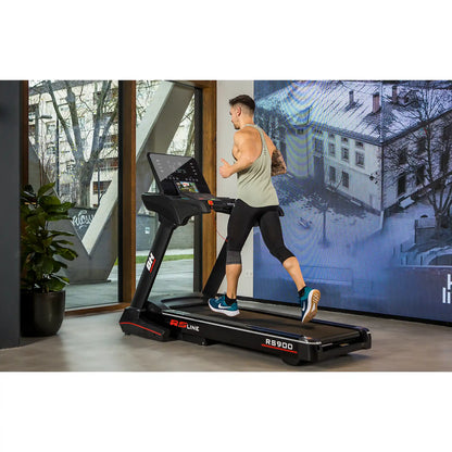 Person running on a treadmill in a modern indoor setting with a large screen displaying an outdoor scene.