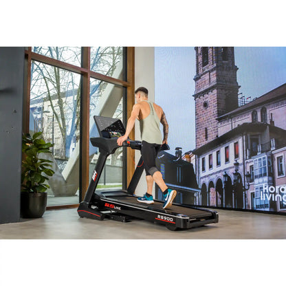 Person using a treadmill in a modern indoor setting with large windows.