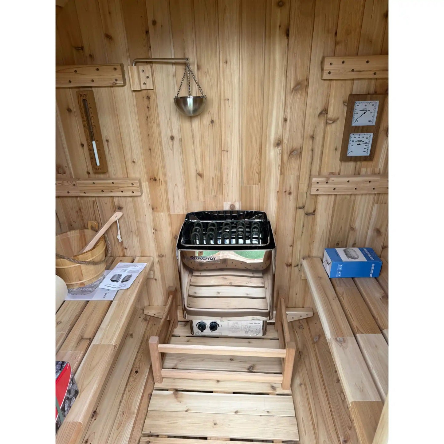 Inside of a wooden barrel sauna showing stove and benches
