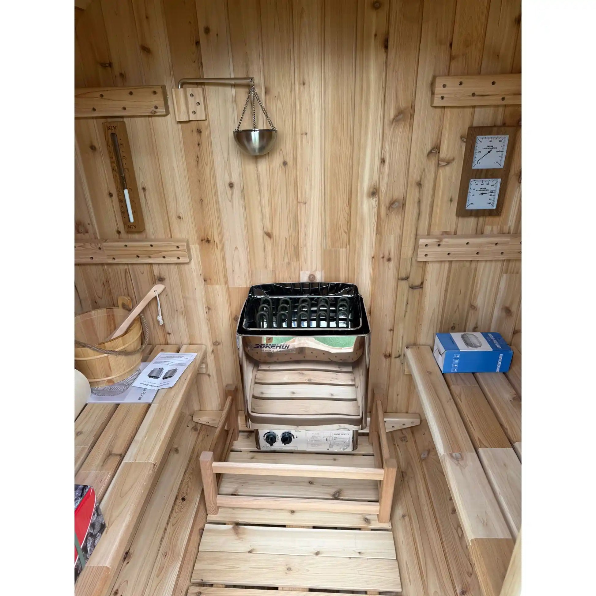 Inside of a wooden barrel sauna showing stove and benches