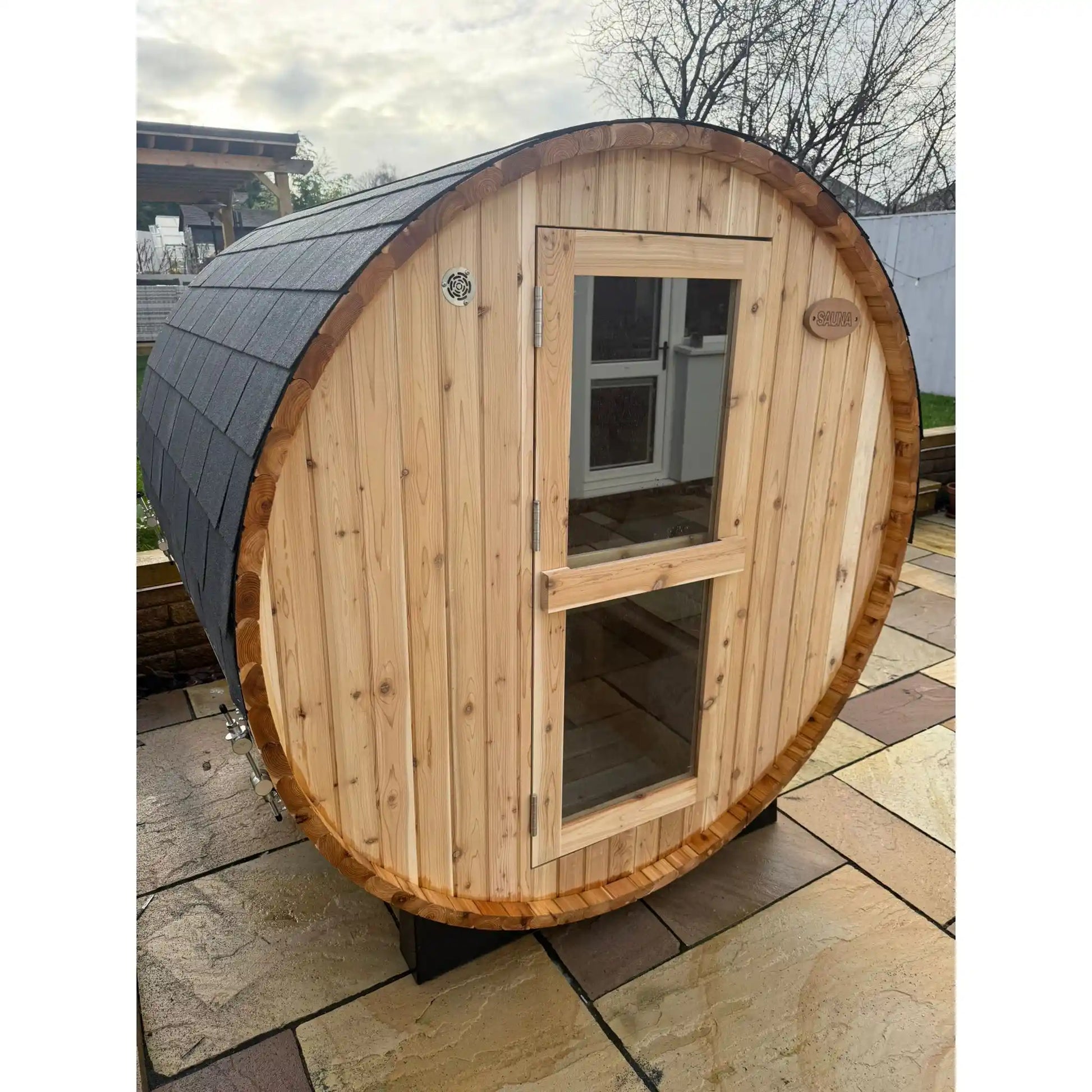 Wooden barrel-shaped sauna on a stone patio