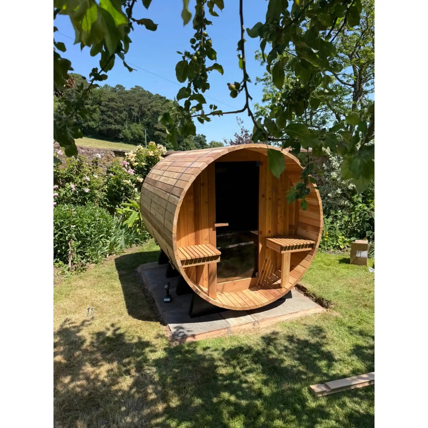 Wooden barrel sauna in a garden setting