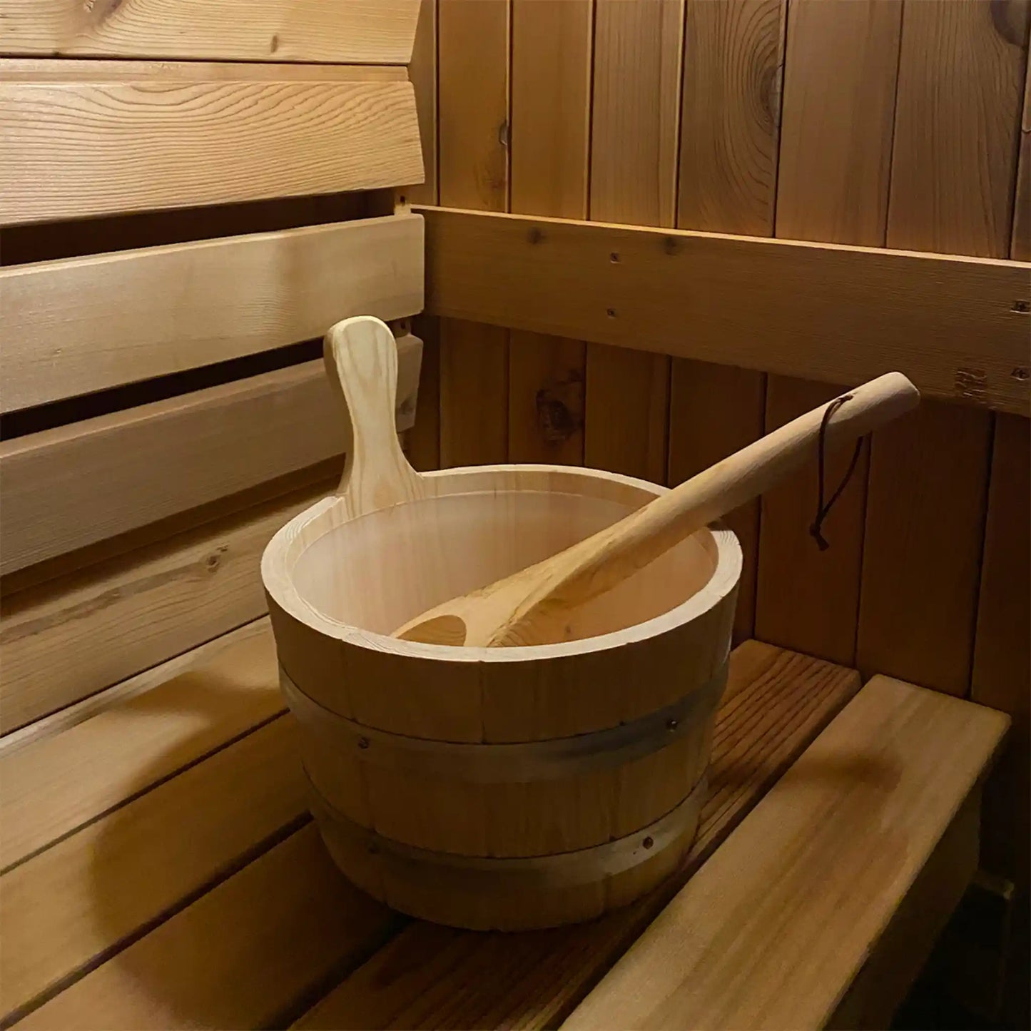 Wooden bucket with a wooden ladle inside a wooden sauna.