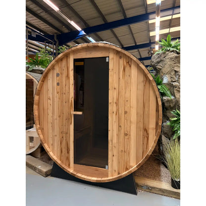 Wooden barrel-shaped sauna with a door inside a warehouse setting