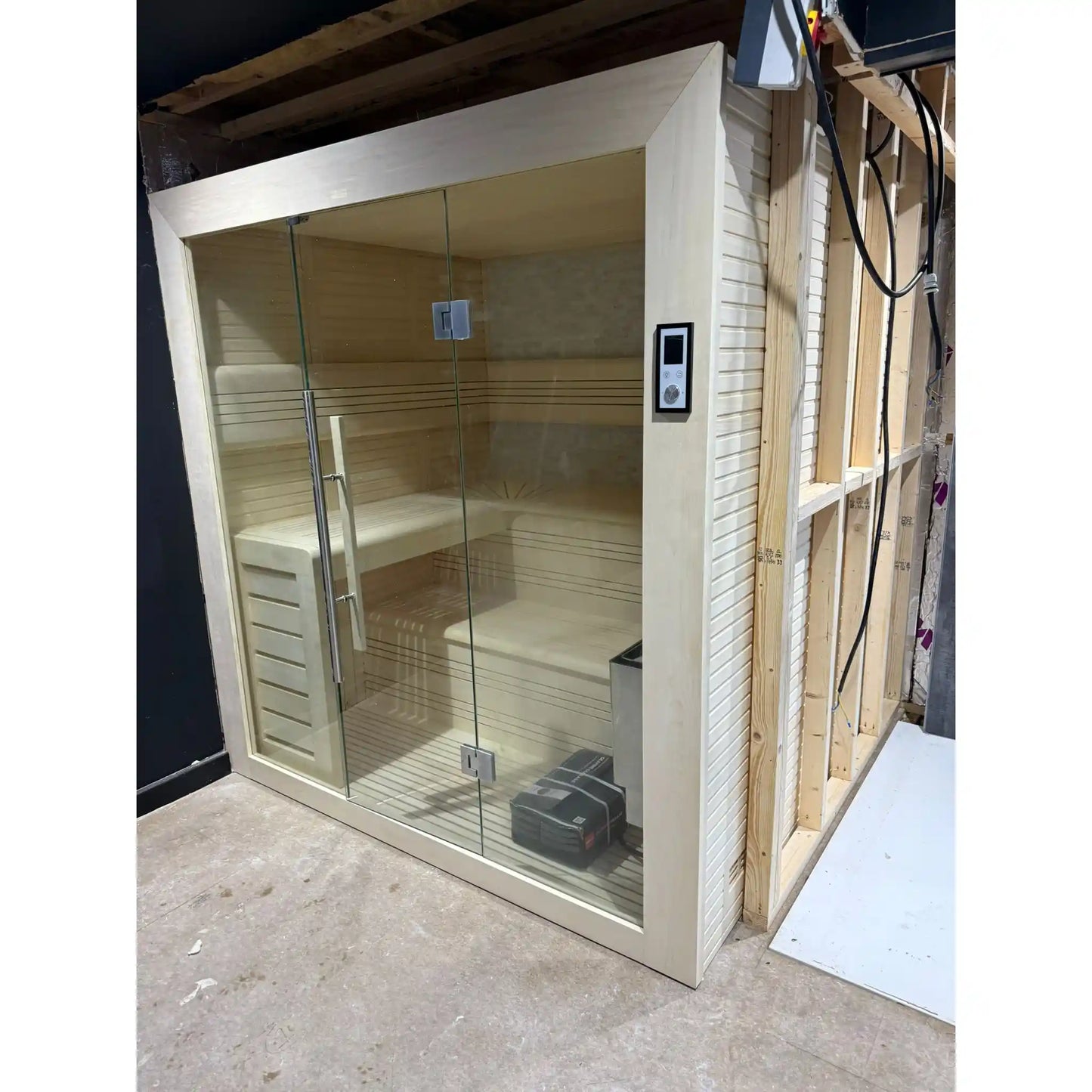 In-progress sauna installation with glass enclosure and wooden interior.