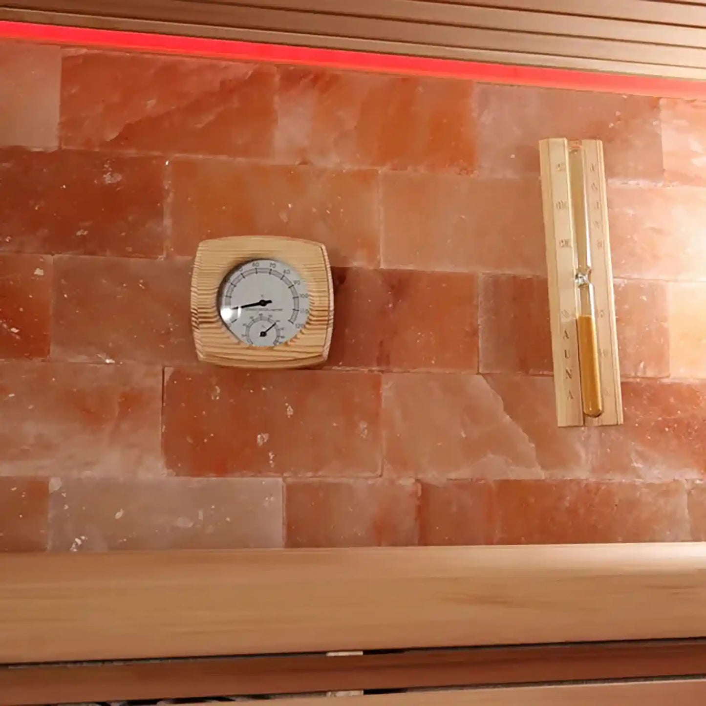Sand timer and thermometer on red stone wall of a sauna
