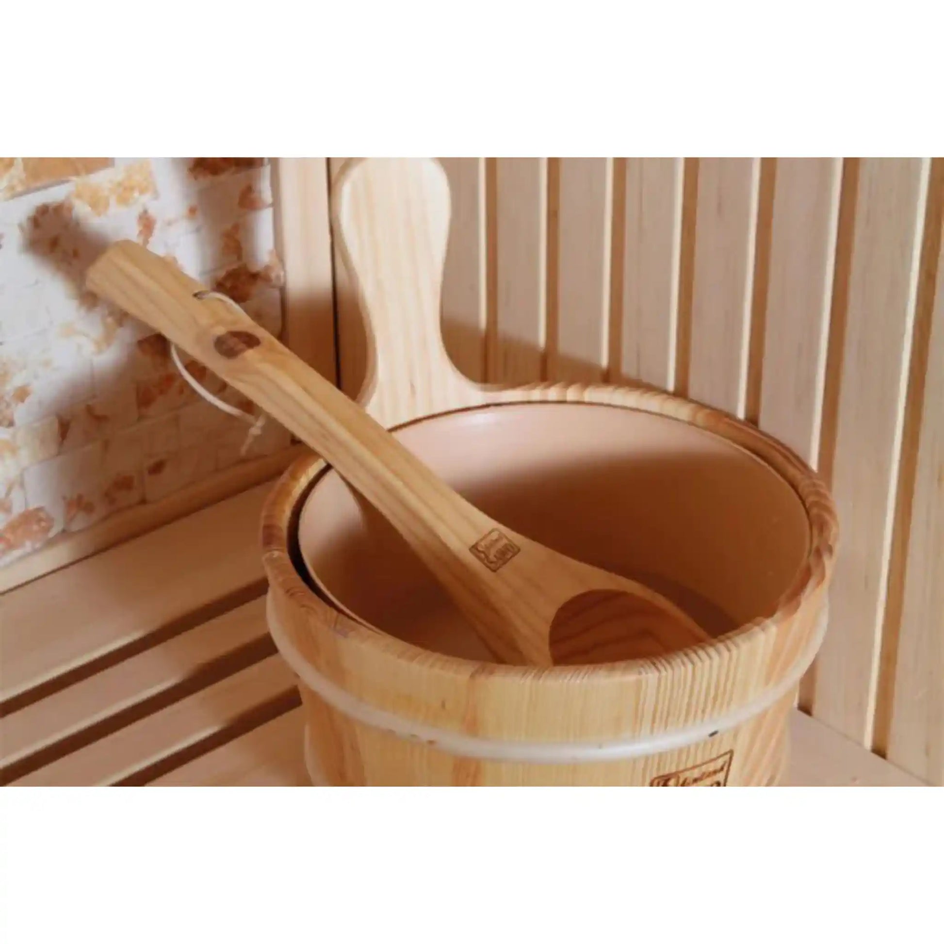 Wooden bucket with a ladle inside, placed on a wooden bench in a sauna setting.