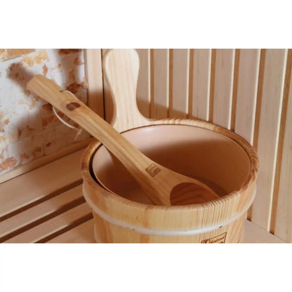 Wooden bucket with a ladle inside, placed on a wooden bench in a sauna setting.