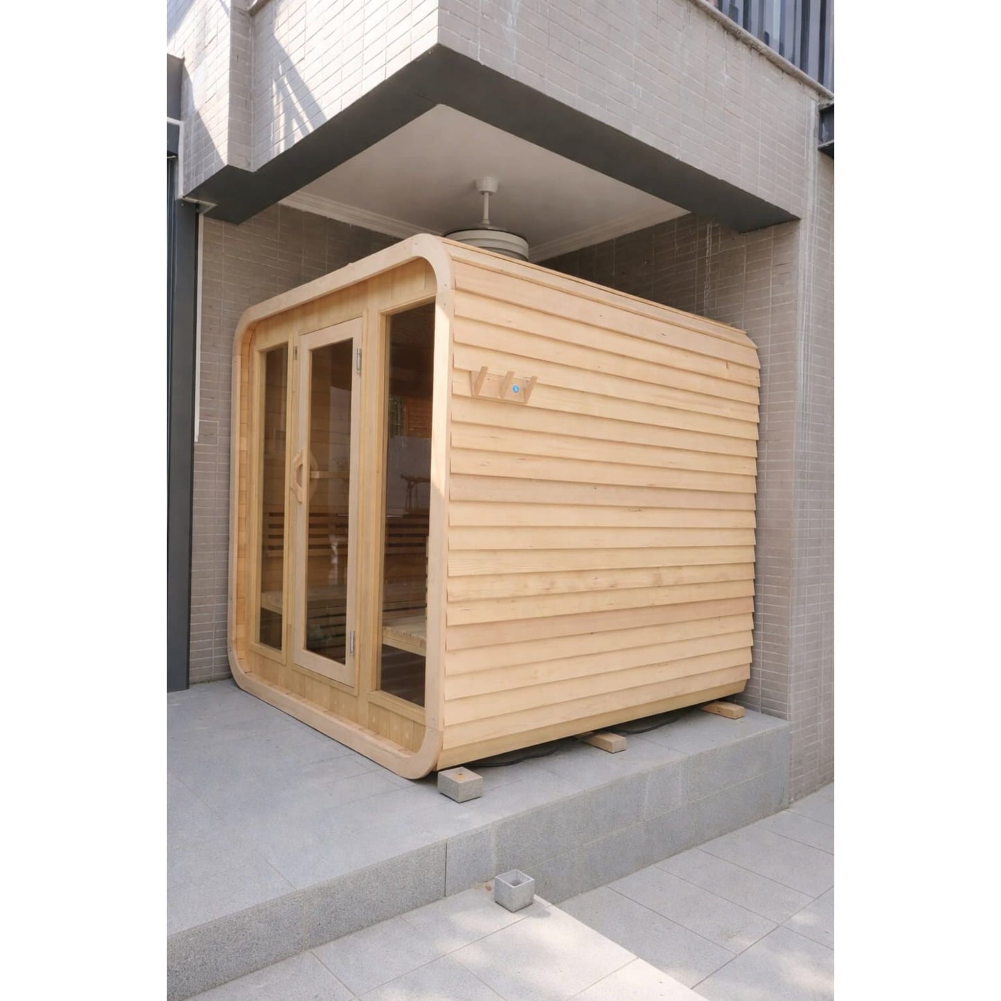 Wooden sauna structure outside a modern building
