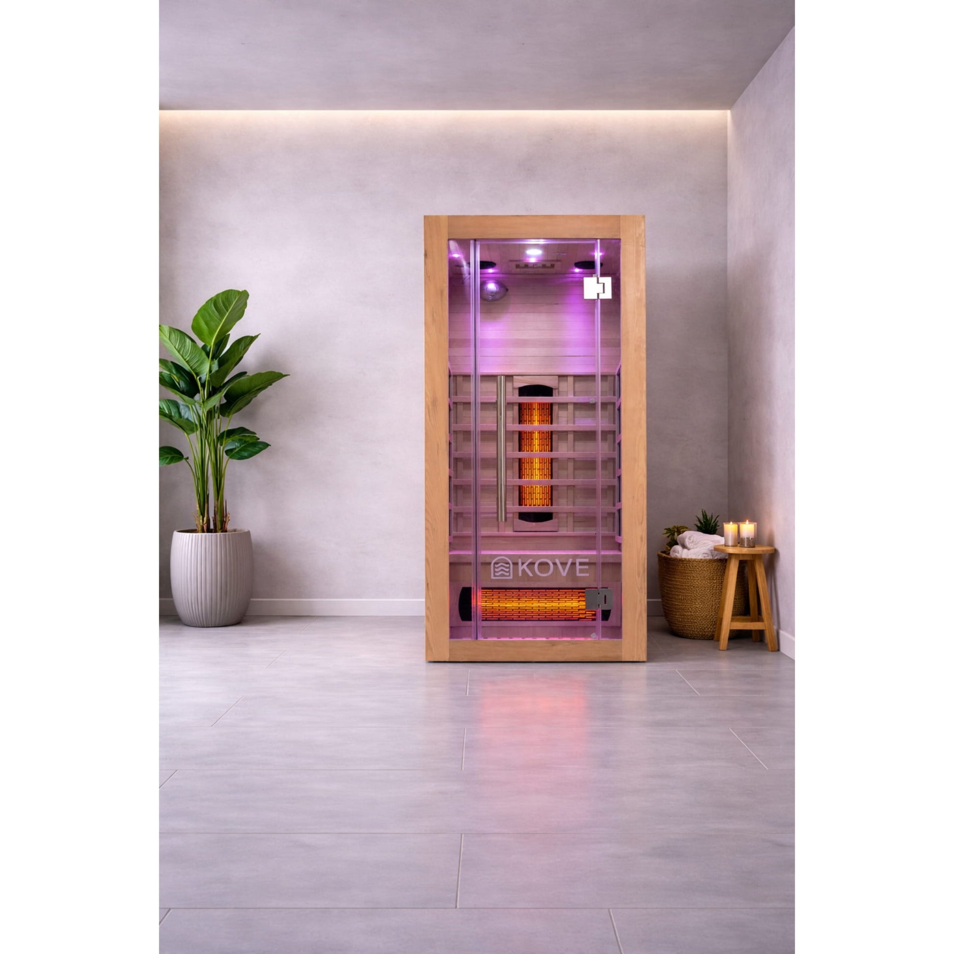 Infrared sauna with Kove logo in a modern room with a plant and candles.