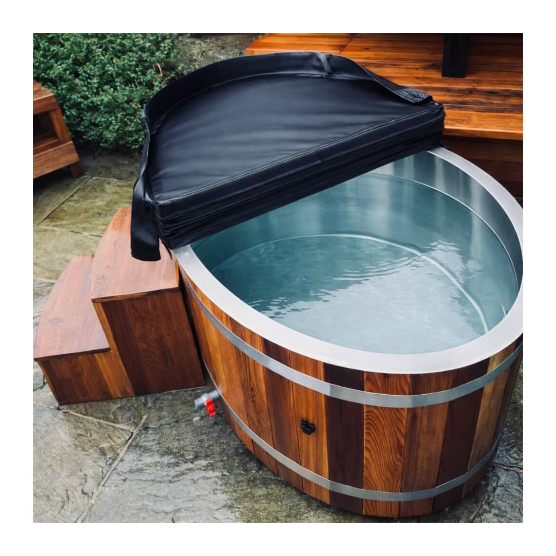 Half covered wooden KOVE Oval Ice Bath filled with water in garden 