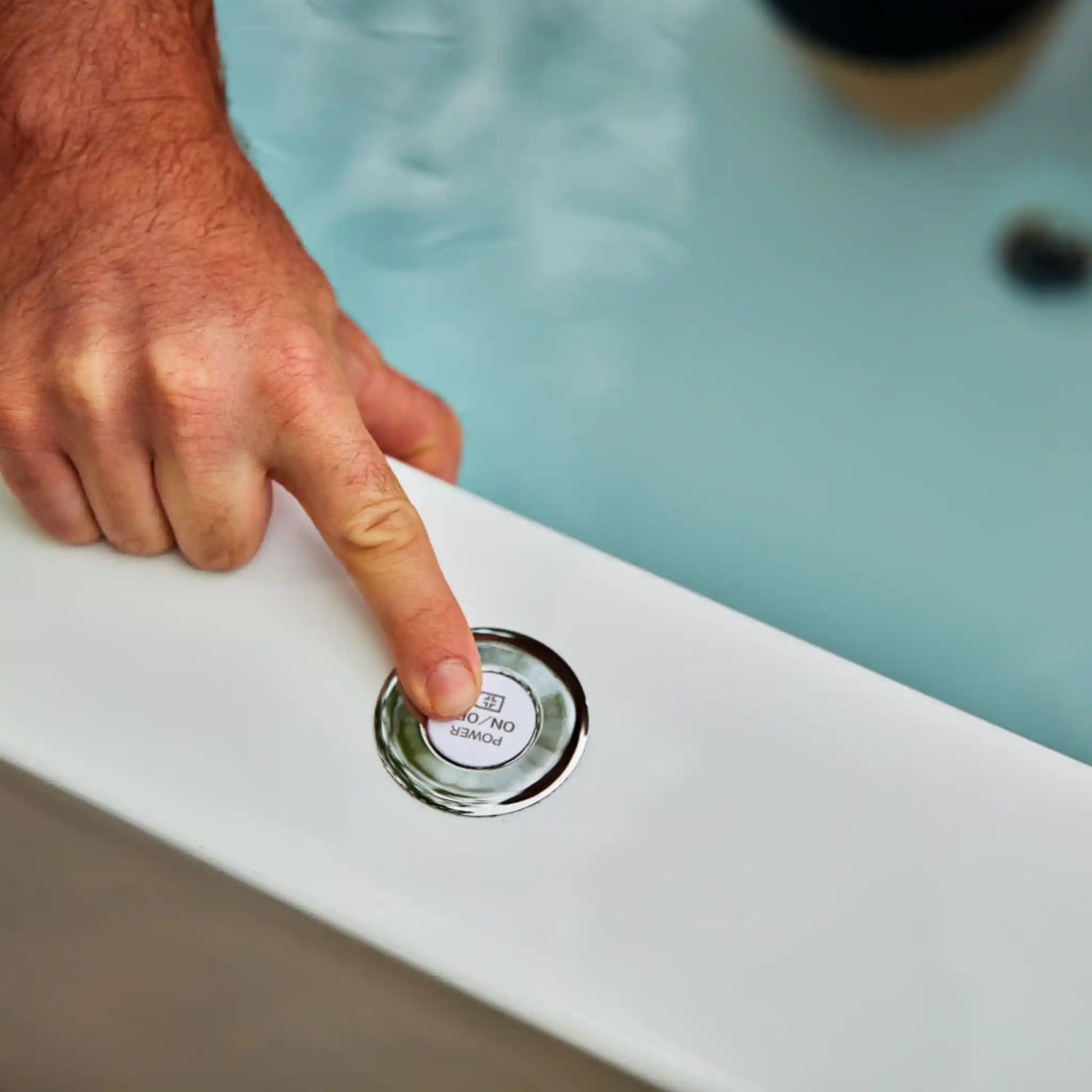 Hand pressing a button on a white ice bath surface with a blurred background