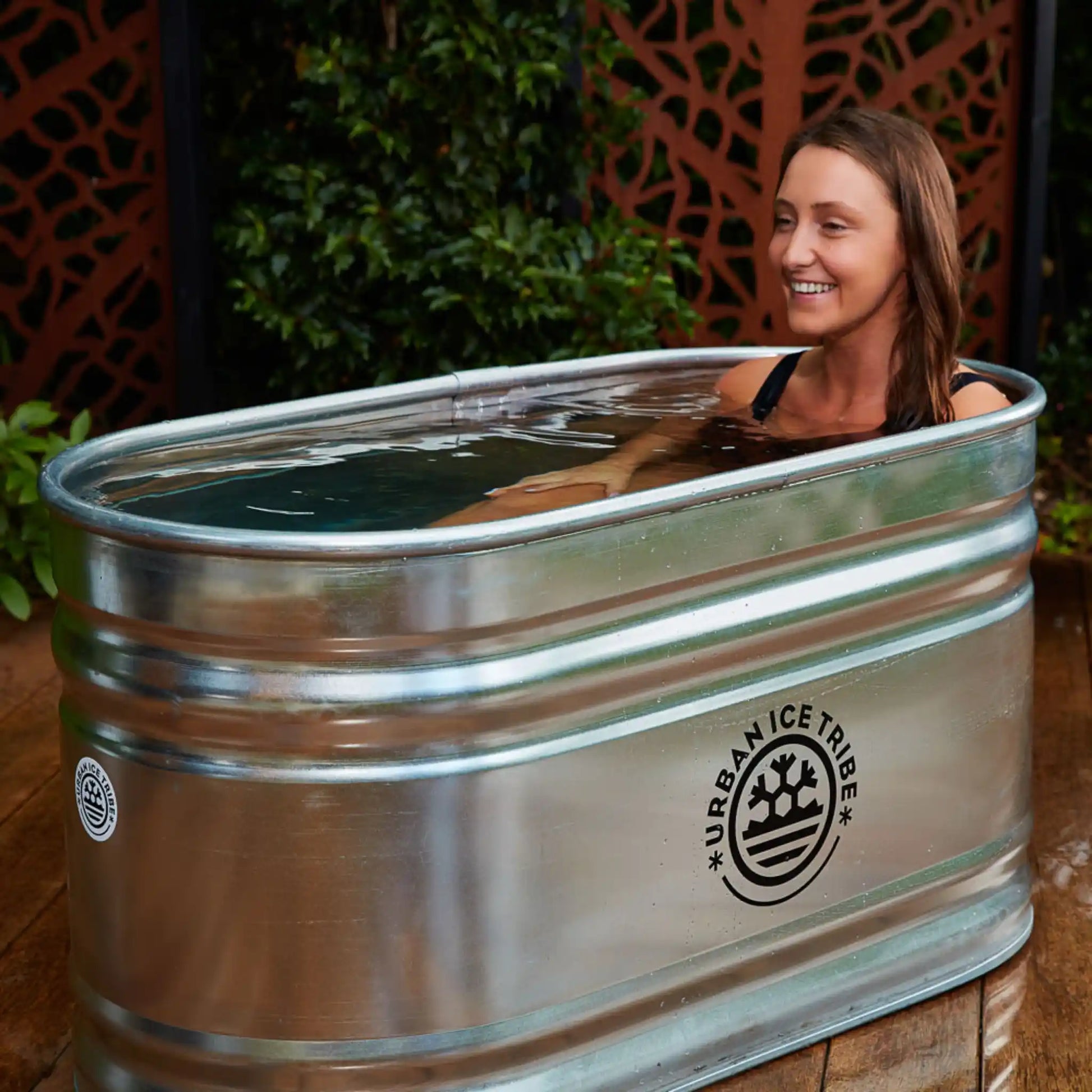 Woman laying in a steel ice bath on decking in a garden