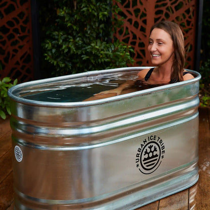 Woman laying in a steel ice bath on decking in a garden